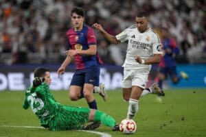 Wojciech Szcesny melanggar Kylian Mbappe dalam laga final Supercopa de Espana antara Real Madrid vs Barcelona, Senin (13/1/2025). (c) AP Photo/Altaf Qadri
